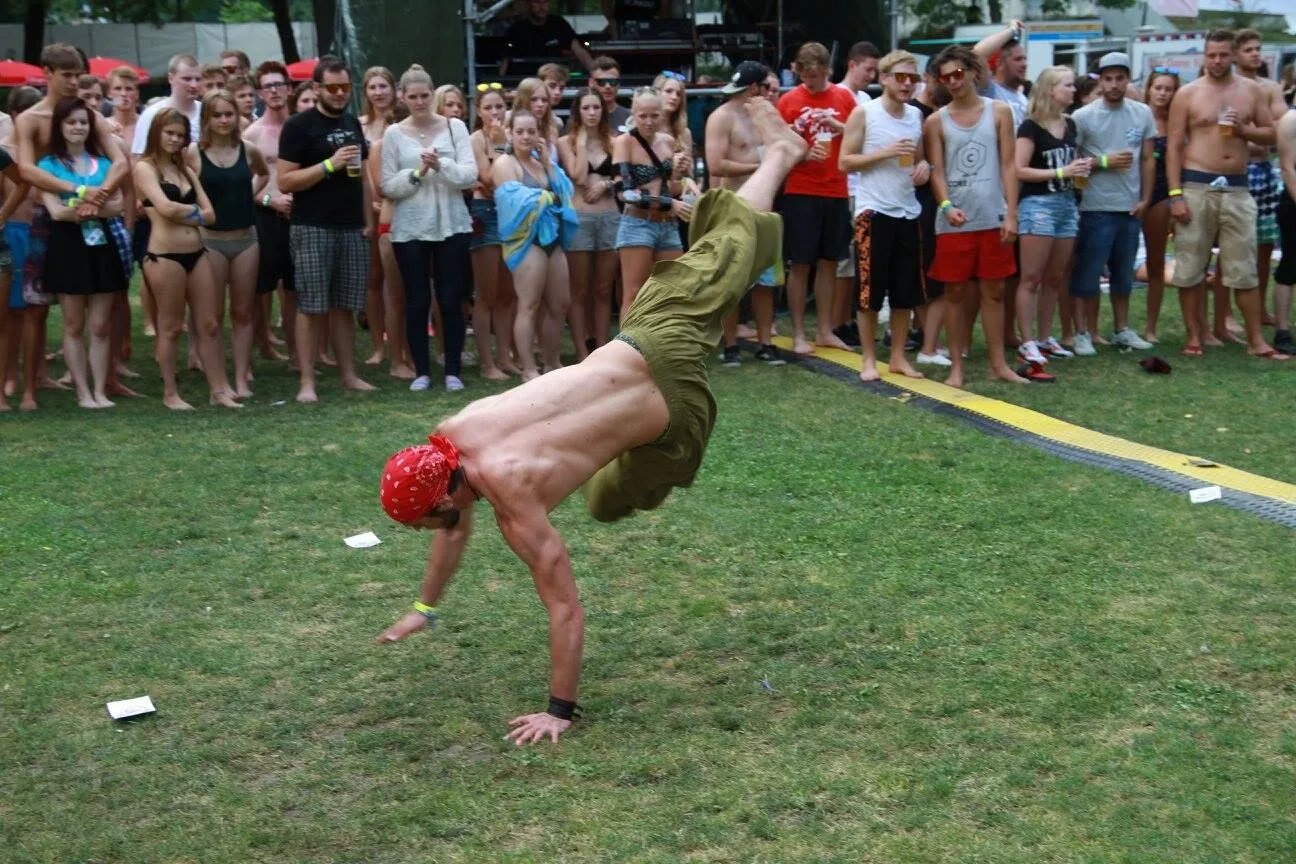 Ein Athlet in einem tiefen Handstand, dahinter eine Reihe Zuschauer.