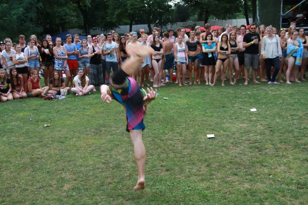 Ein Sprungkick in der Luft vor Zuschauern auf einer Wiese.
