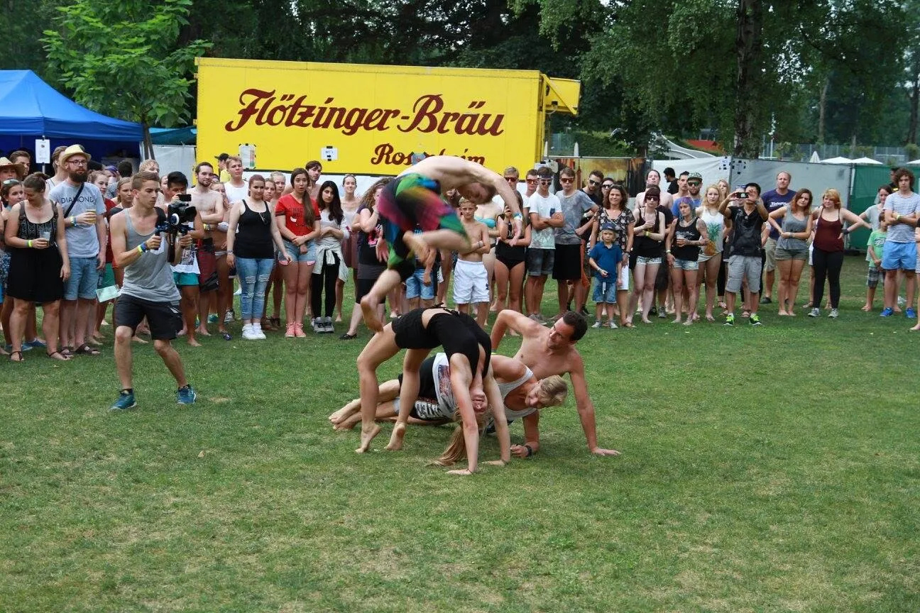 Mehrere Athleten bilden gemeinsam eine Menschenpyramide vor Publikum.