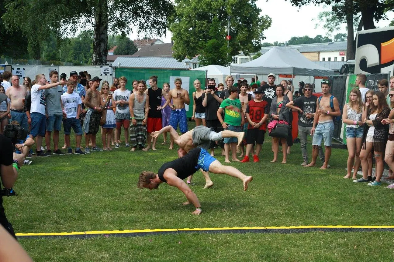 Ein Athlet in der Luft über der Showfläche, im Hintergrund das Festivalpublikum.